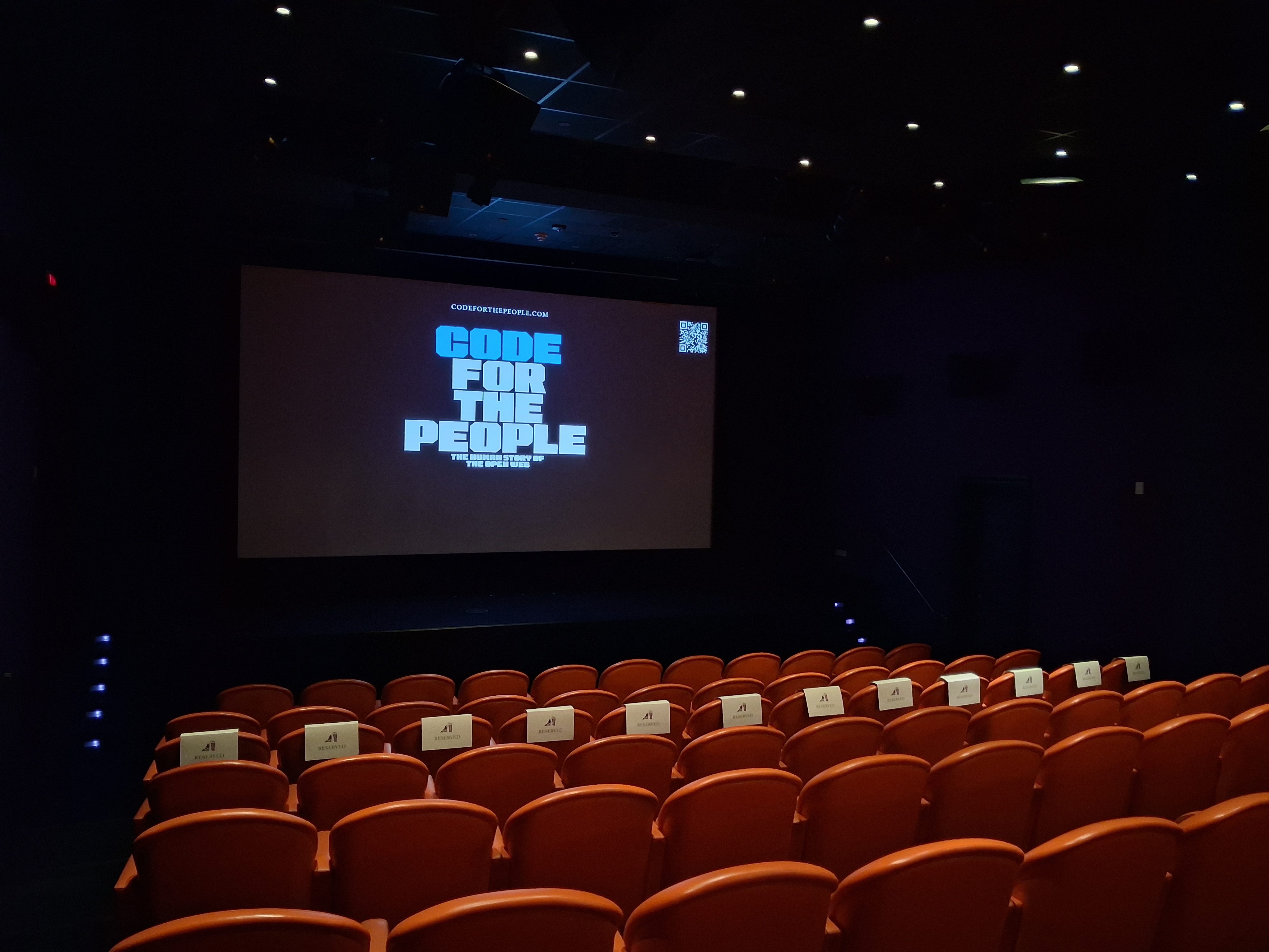 Empty cinema auditorium with orange seats prior to the Code for the People documentary screening.